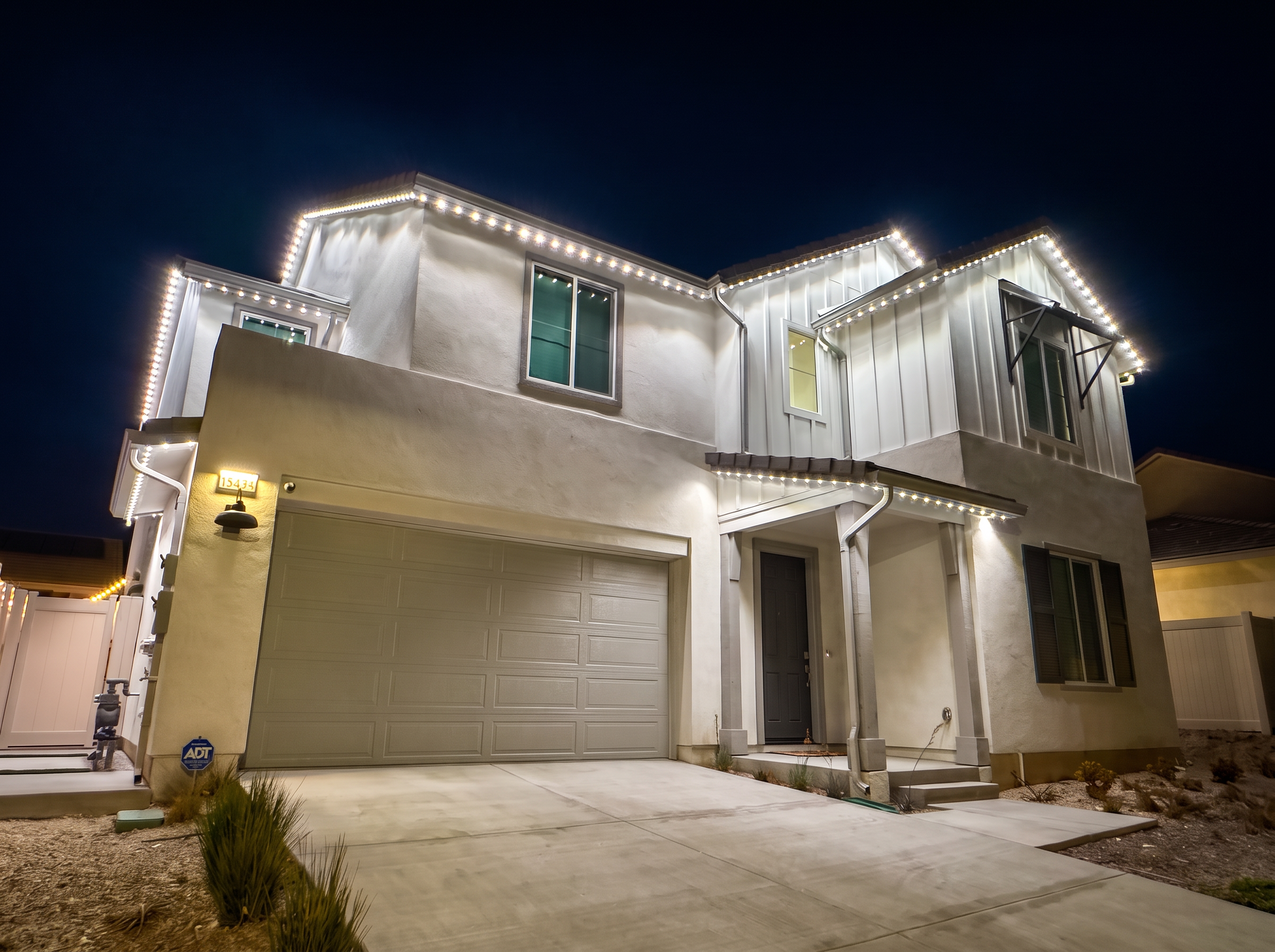 Two-story home outlined with permanent white LED roofline lighting at night